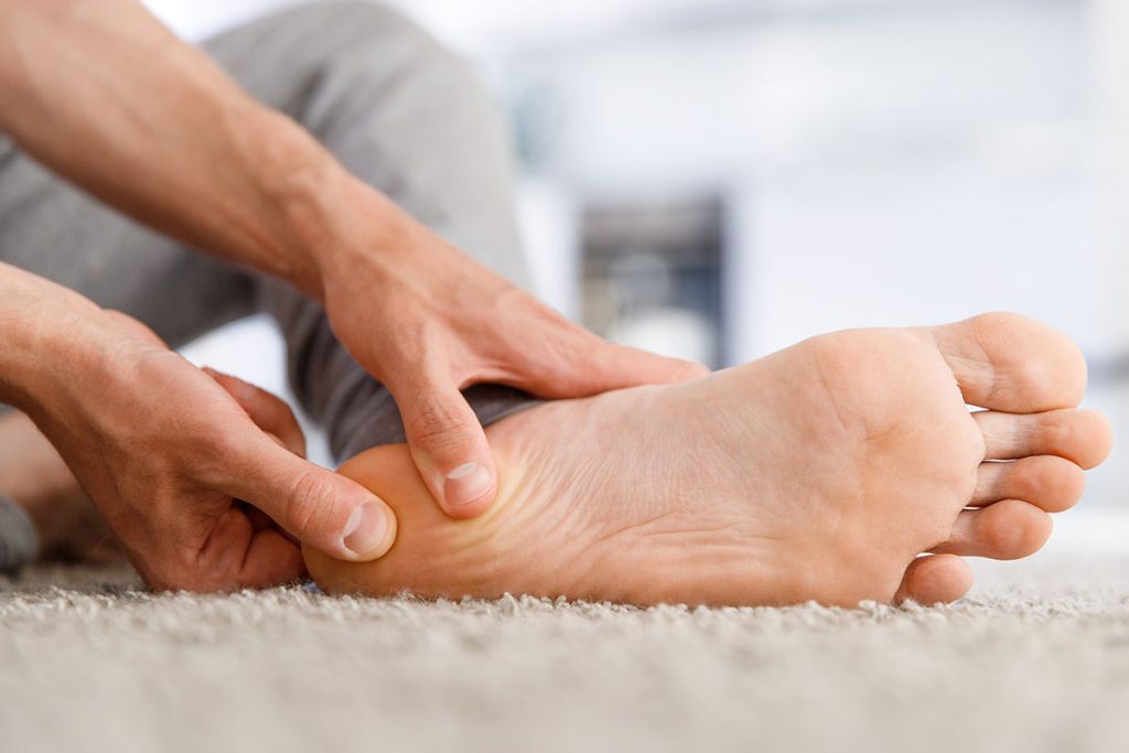 Man hands giving foot massage to yourself after a long walk, suffering from pain