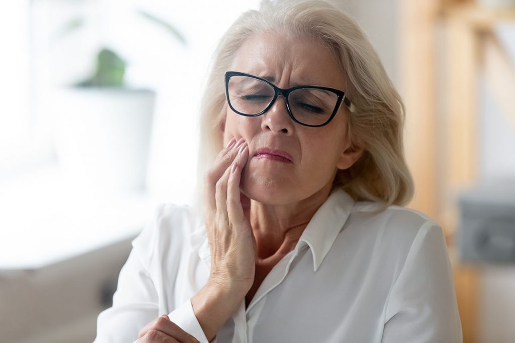 Hurt senior female worker in glasses feel stressed suffering from severe jaw pain